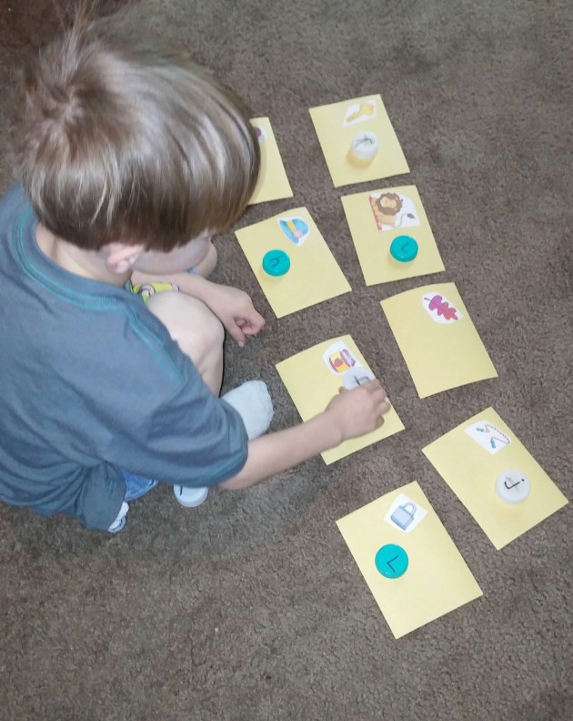 Kona matches the letter of the beginning sound with the picture cards.